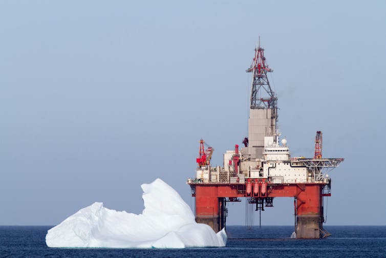 Uma plataforma de petróleo com um grande iceberg à sua frente.